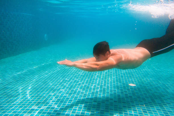 latin child boy swimmer underwater wearing cap and goggles in a swimming training at the Pool in Mexico Latin America