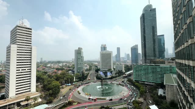 Jakarta - April 6th 2024 : View of Jakarta traffic at downtown city centre, the central business district CBD and the famous Bundaran HI roundabout with Jakarta skyscrapers under the sunny blue sky.