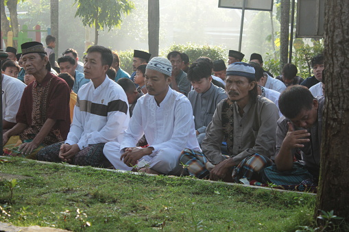 wonogiri, indonesia - april 10, 2024 : moment of eid al fitr in sunny morning. moslems praying together at the field. annual moment in moslem community after a month doing fasting ramadhan. gathering in field with family, friend and everyone to praying eid al fitr. man praying eid al fitr in the morning