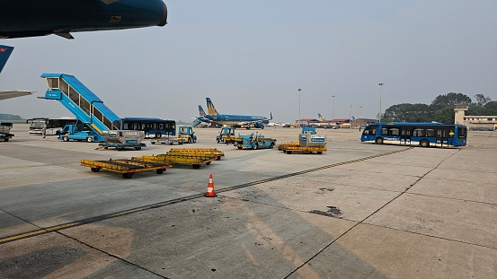 Ha Noi, Vietnam - April 1, 2024: View from the airplane window to the runway. Airport staff are preparing the plane for takeoff in Noi Bai airport, Hanoi, Vietnam.