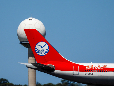 A Sichuan Airlines Airbus A330-343 plane, registration B-308F, has landed from the north at Sydney Kingsford-Smith Airport as flight 3U3883 from Chengdu .  In the background is the airport's weather measuring installation, which appears in the shape of a golf ball.  This image was taken from Kyeemagh, Botany Bay, on a hot and sunny afternoon on 19 January 2024.
