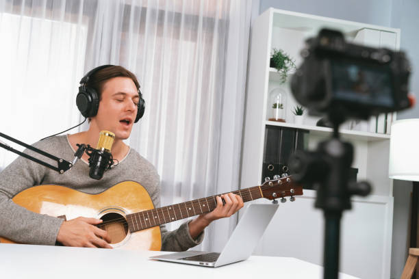 istock Smart singer recording by camera, playing guitar along singing. Pecuniary. 2148229510