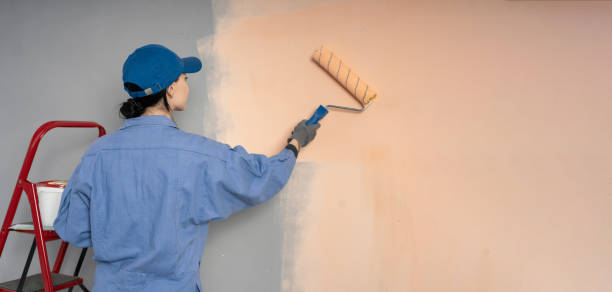 istock Rear view of a woman painter painting a wall with a roller 2148229580