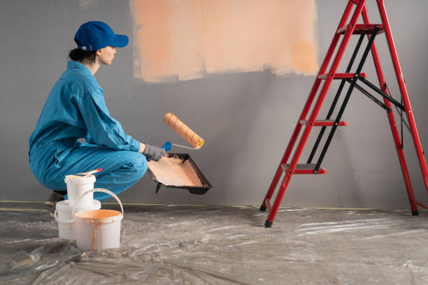 istock Side view of painter with cap squatting ready painting a wall with paint roller. repair, building and home 2148229592