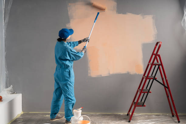 Builder or painter in cap Paints walls with long painting roller. business, building, renovation and people Builder or painter in cap Paints walls with long painting roller. business, building, renovation and people concept house painting service stock pictures, royalty-free photos & images