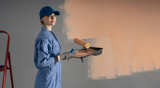 Painter with painting roller looking at camera. Cute worker with paint roller. Professional painter woman. Banner. Copy space
