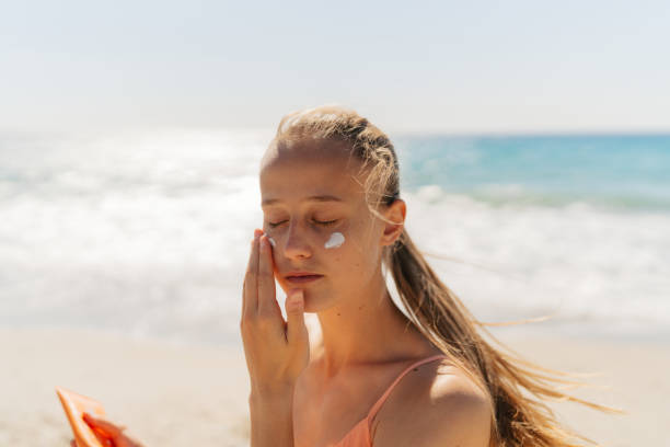istock Young woman applying sunscreen on her face while at the beach 2148229610