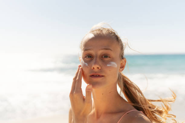 istock Young woman applying sunscreen on her face while at the beach 2148229622