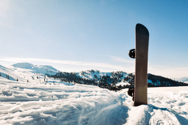 istock Snowboard With Black And White Strips Standing In Snow With Winter Mountains In Background 2148230081