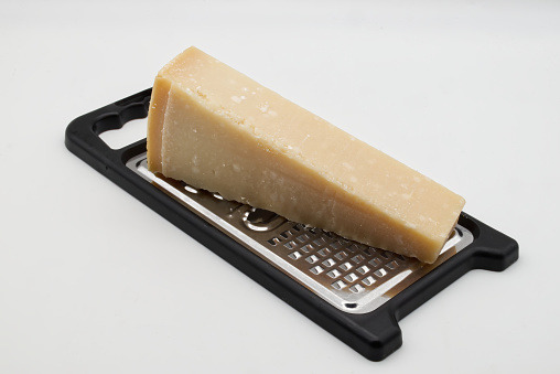 Metal grater with Parmigiano Reggiano cheese isolated on white