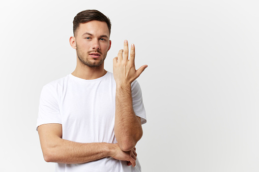 Pensive young thoughtful tanned handsome man in basic t-shirt cross hands think about business decision posing isolated on white studio background. Copy space Banner. People emotions Lifestyle concept