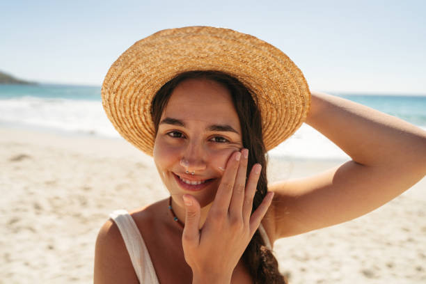 istock Young woman applying sunscreen on her face while at the beach 2148230682
