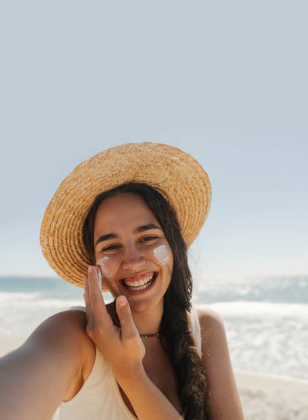 istock Young woman applying sunscreen on her face while at the beach 2148230731