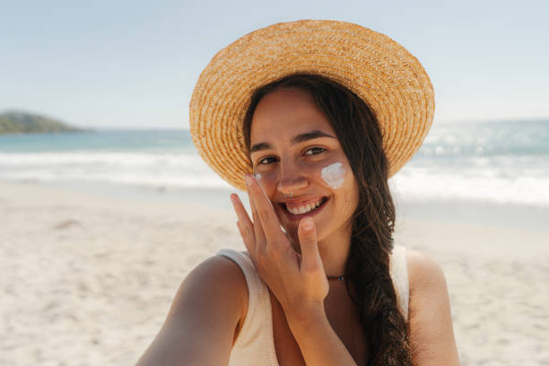 istock Young woman applying sunscreen on her face while at the beach 2148230732