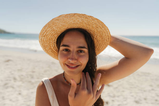 istock Young woman applying sunscreen on her face while at the beach 2148230814
