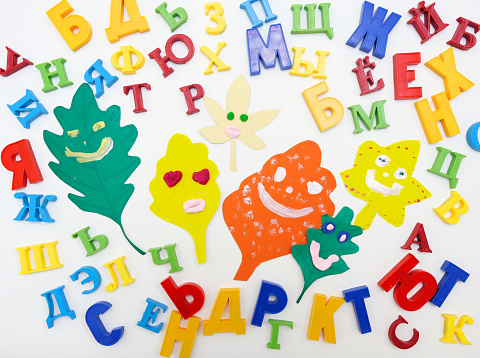 Funny smiling face on paper leaves,  Colorful of randomly placed letters of the Russian alphabet on white background