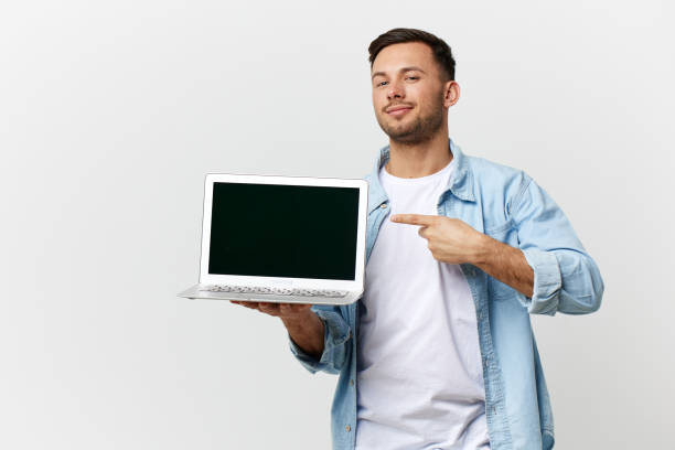 istock Cheerful friendly tanned handsome IT professional man in casual basic t-shirt point finger at laptop posing isolated on white studio background. Copy space Banner Mockup. Electronics repair concept 2148231450