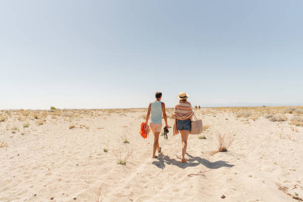 Photo of a romantic couple, going towards the sea, across the sandy beach
