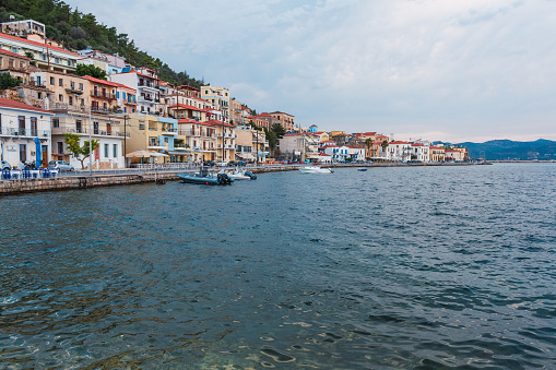 the peaceful promenade of a Mediterranean village lined with colorful buildings and leisure boats moored along the clear blue water