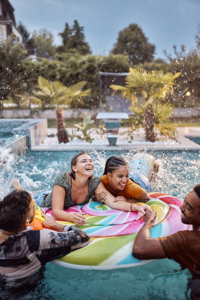 istock Young cheerful friends talking on inflatable raft at the pool. 2148233901