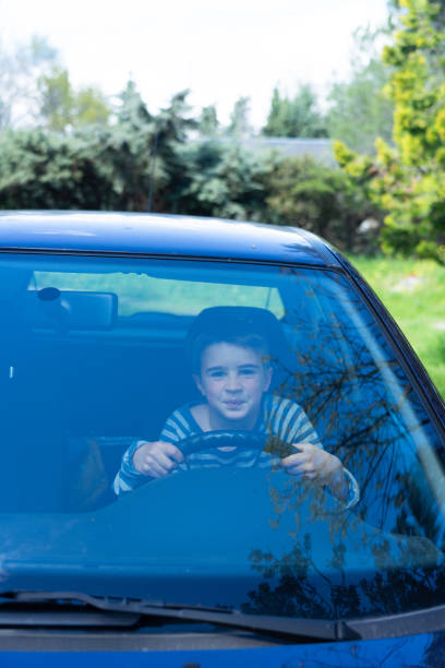 istock Naughty child playing pranks while driving an adult car 2148236055