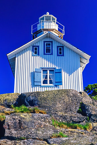 Lidköpinga, Sweden-May, 2020: Old wooden lighthouse on a cliff with a blue sunny sky