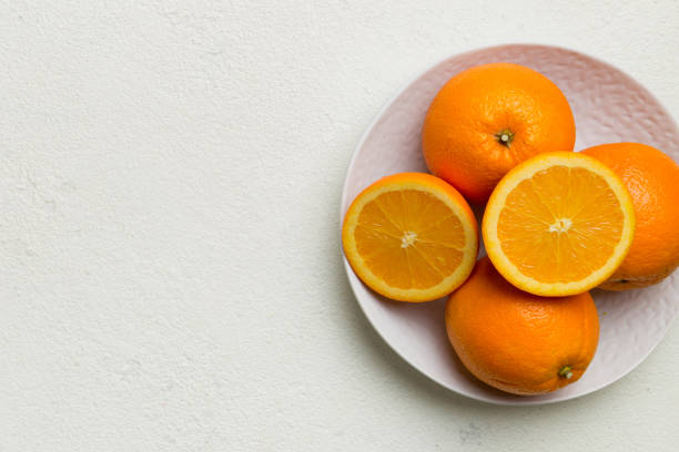 istock Flat lay of Fresh orange fruit with sliced in plate on Colored background. Top view with copy space 2148236641