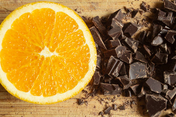 A freshly cut orange lie next to the deep, dark allure of chocolate chunks.