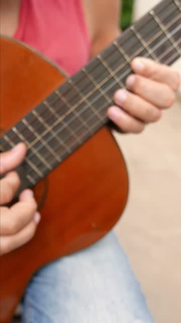 Person playing an acoustic guitar. Guitar strings working. Person strumming a guitar. Someone plucking a guitar. Guitarist playing a song on his guitar. Person playing guitar chords. Musical notes