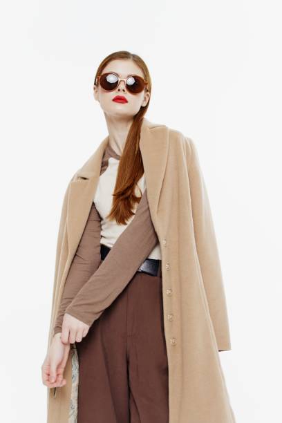 istock Stylish red-haired lady with glasses and a coat on a white background 2148237978