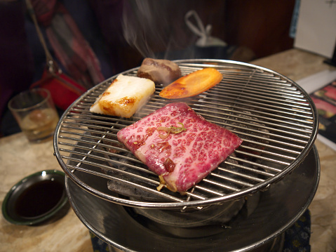 Cooking japanese wagyu marbled beef slice on round yakiniku grill