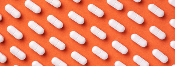 istock Orange and red medicine background with white pills and tablet, macro. 2148240599