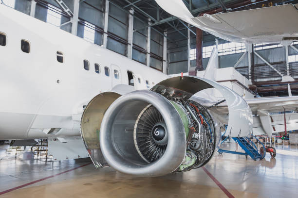 White passenger plane in the aviation hangar. Airplane under maintenance. Checking mechanical systems for flight operations