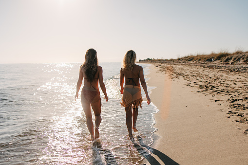 Two female friends walking on the beach early in the morning