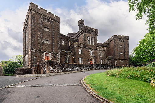 Stirling - United Kingdom. May 21, 2023: Nestled in Stirling historic landscape, the Old Town Jail exudes Victorian austerity, its dark masonry framed by verdant trees and a dynamic sky