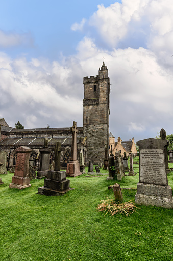 Stirling - United Kingdom. May 21, 2023: Vertical view of the Church of the Holy Rude ancient tower, standing vigil over the weathered gravestones in its historic cemetery. Stirling, Scotland