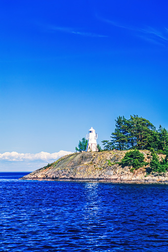 Lighthouse on a rocky islet in the summer