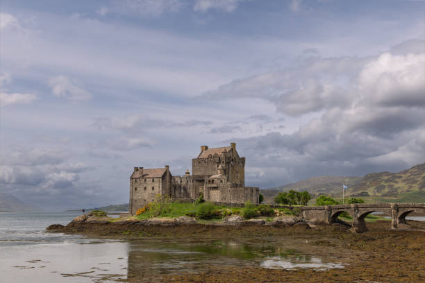 le château d’eilean donan reflète son passé chargé d’histoire dans le calme du loch, flanqué d’un pont historique et des collines ondulantes des highlands écossais - scotland castle highlands region scottish culture photos et images de collection