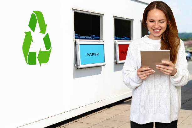 istock Woman uses her digital tablet while standing next to a separate waste collection station on street 2148242219