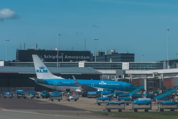 Schiphol Airport, Amsterdam, Netherlands - April 10, 2024: KLM airplanes at the terminal waiting for passengers. Aircraft control tower in the background.