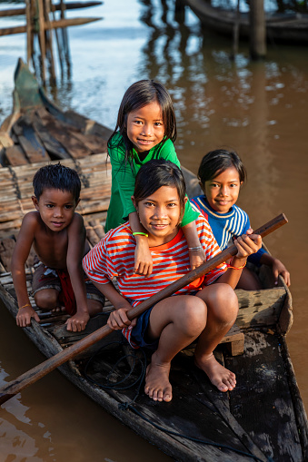 Cambodian kids rowing a boat in village near Tonle Sap, Cambodia