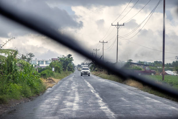 Kuala, North Sumatra, Indonesia - January 25th 2024: Rural road on a rainy day seen from the car