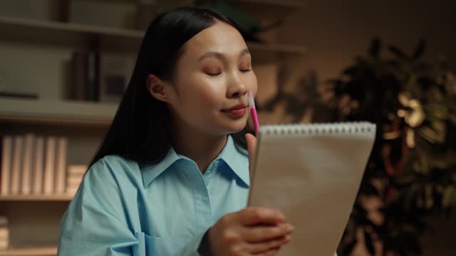 Thoughtful Young Asian Woman Brainstorming Ideas in a Home Library at Evening