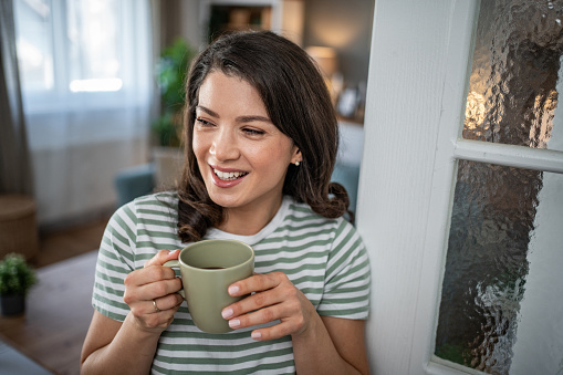 Calm spring morning - A young woman enjoys her morning coffee in her apartment