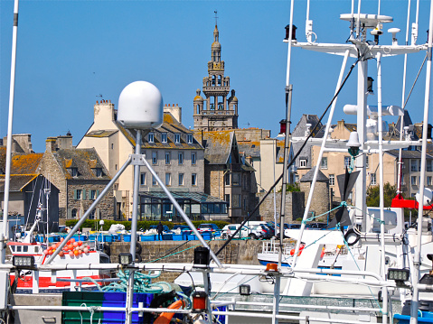 Closeup of fishing ship in the port of Roscoff and its bell tower, a commune in the Finistère département of Brittany in northwestern France