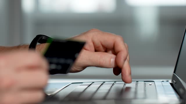 Male hands typing credit card number on computer keyboard