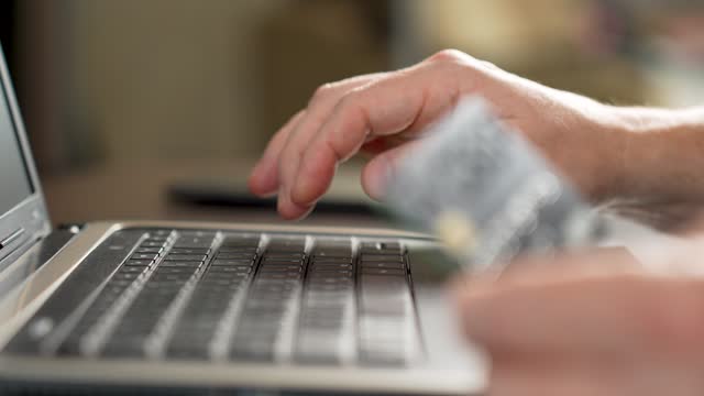 Male hands typing credit card number on computer keyboard
