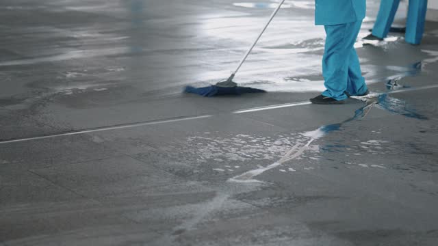 Close-up of housekeepers sweeping the floor with mops