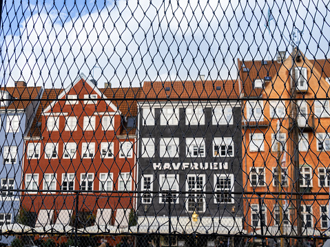 Copenhagen, Denmark - 9 October, 2022: A view through the chain-link fence towards the most touristy part of Copenhagen, with the old buildings along the canal