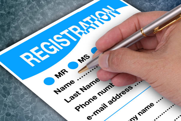 Someone holding pen in hand to filling blank register form.
